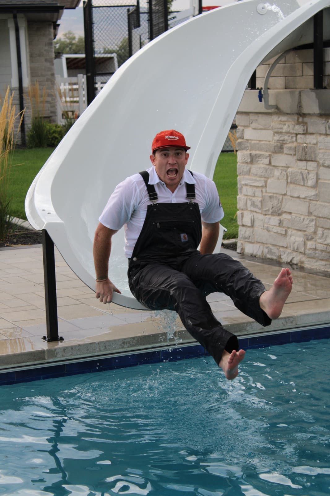 Cory, founder of Planned Home Maintenance, going down a waterslide in full work uniform