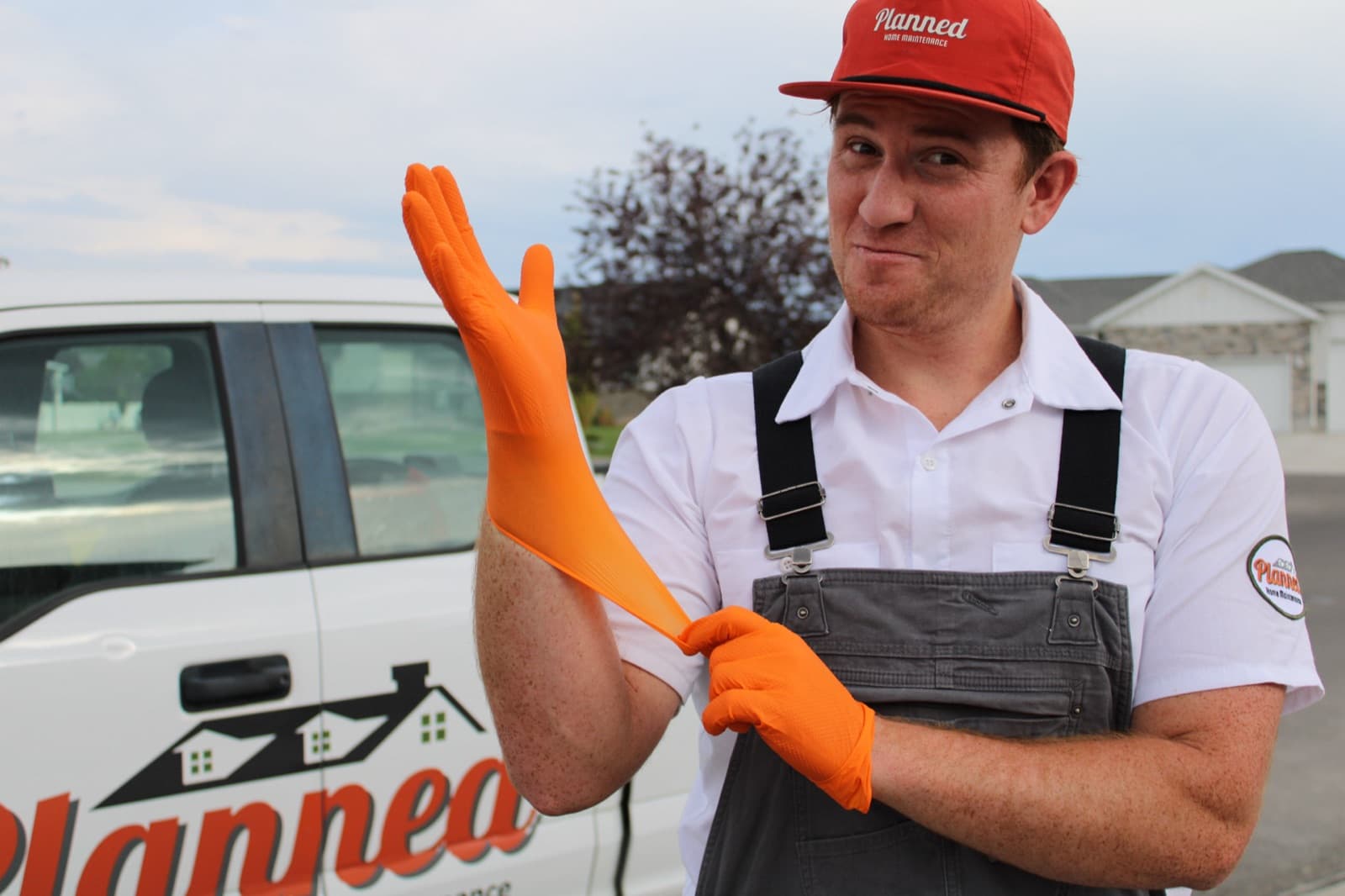 Planned technician pulling on work gloves in front of the branded service truck